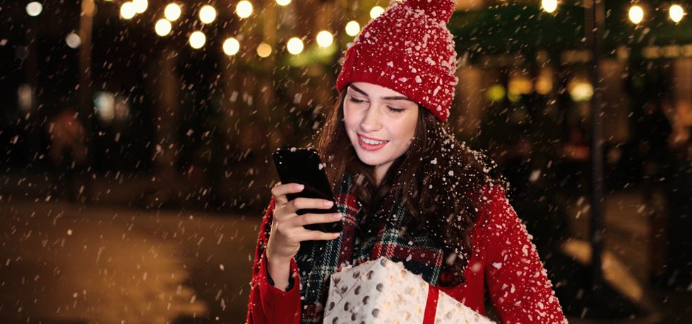 a woman reading text message and holding Christmas present