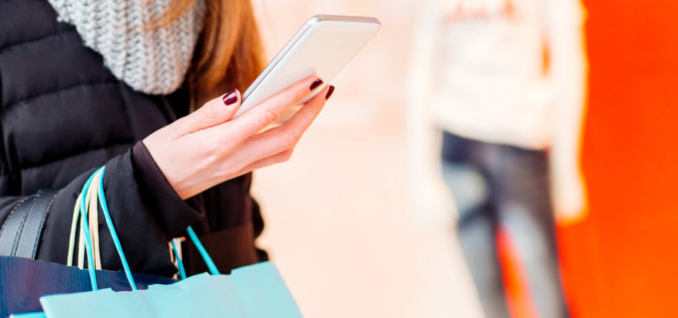 Woman with shopping bags, looking products in the mobile phone