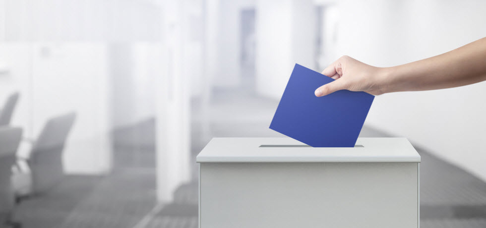 Voter inserting envelope in ballot box