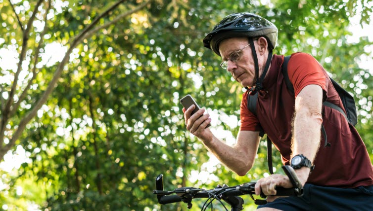 Senior cyclist reading text warning on the mobile phone