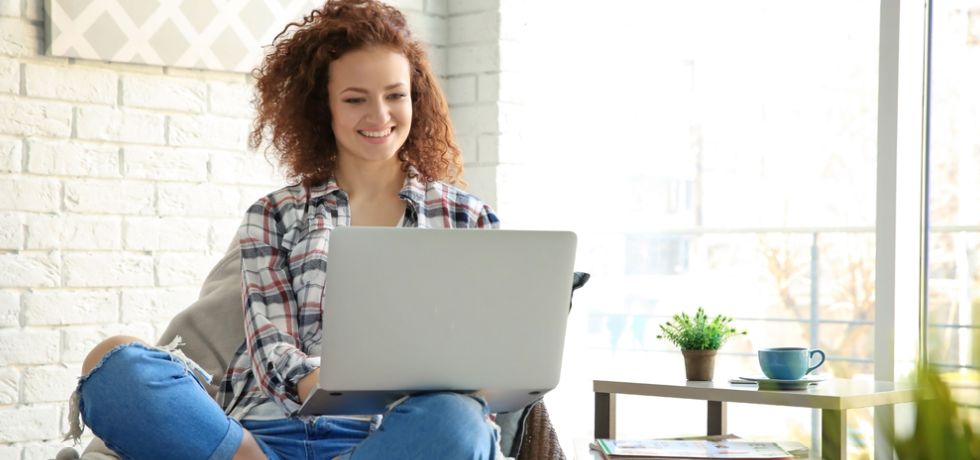 Young woman sitting at home using a laptop