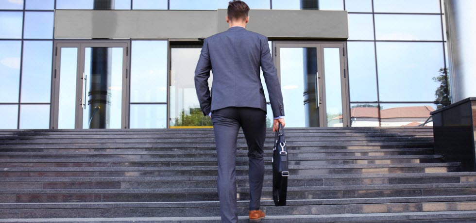 Businessman walking up the stairs towards office building