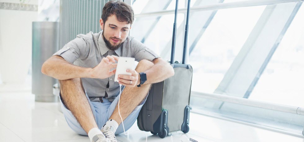 a man charging his phone and waiting for his flight at the international airport