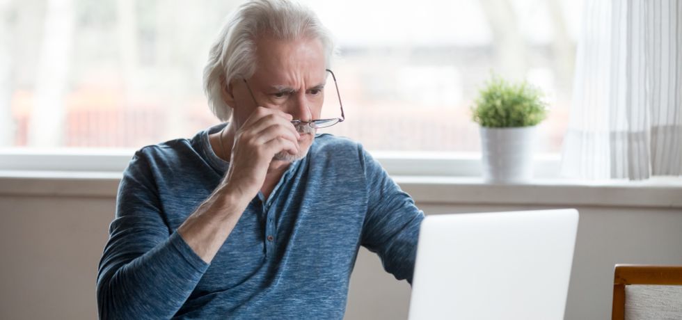 deceived frustrated senior mature man taking off glasses to look at laptop