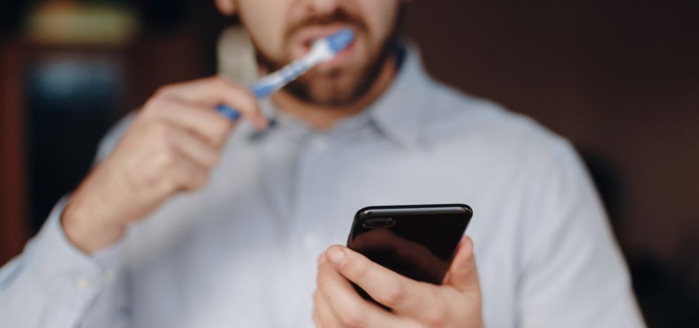 man looking smartphone during teeth wash