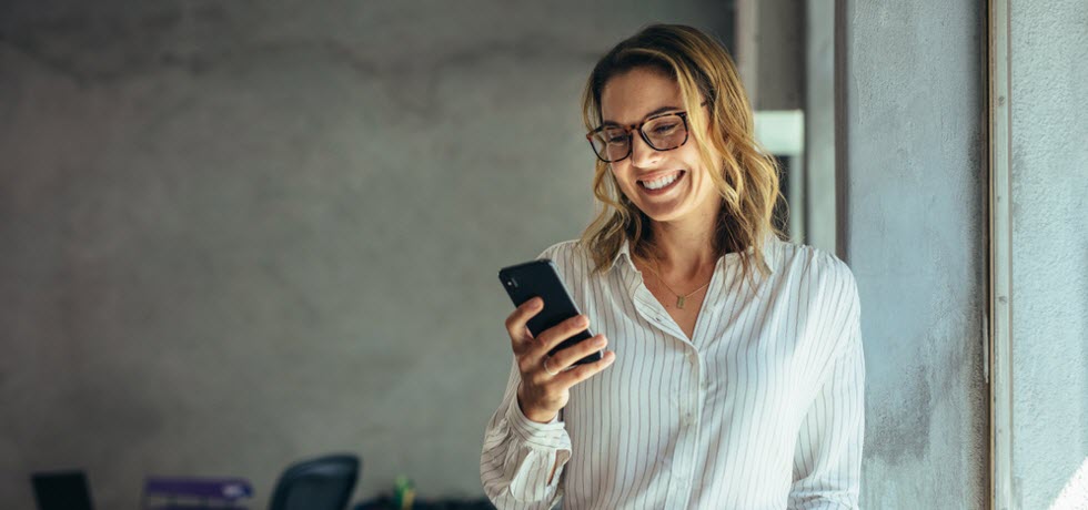 A smiling woman reads a personalized text message