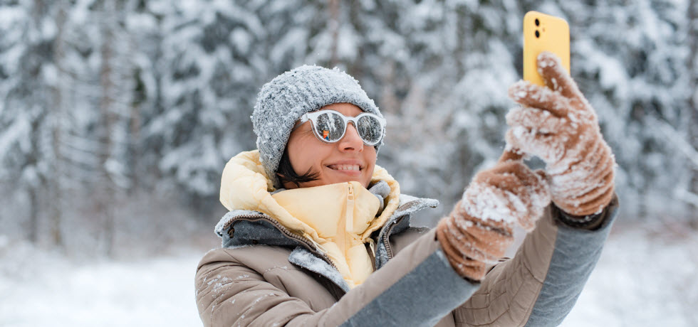 female taking photos with mobile phone in nature on frosty day